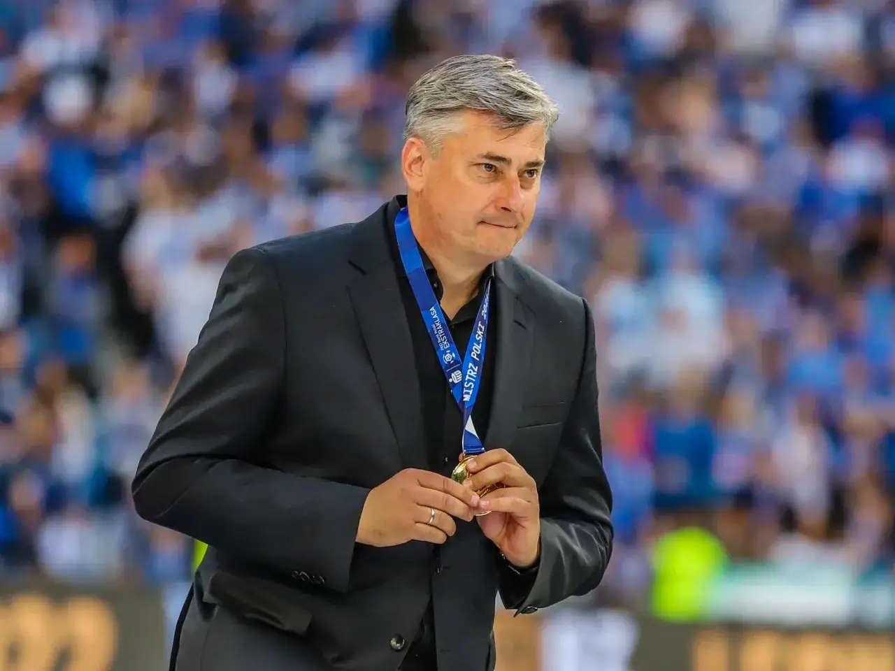 Maciej Skorża, po zwycięstwie, trzyma medal. W tle tłum kibiców. Ostatnio jego żona choroba była tematem medialnym.